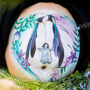 Bemalung auf Schwangerschaftsbauch mit einer Pinguinfamilie
