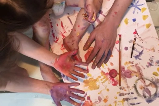 Bunte Kinderhände und Erwachsenenhand beim gemeinsamen Malen – kreative Familienmalerei voller Farben
