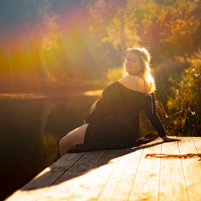 Babybauch-Shooting auf einem Holzsteg am Wasser – Schwangerschaftsfoto mit Sonnenuntergang und warmem Licht