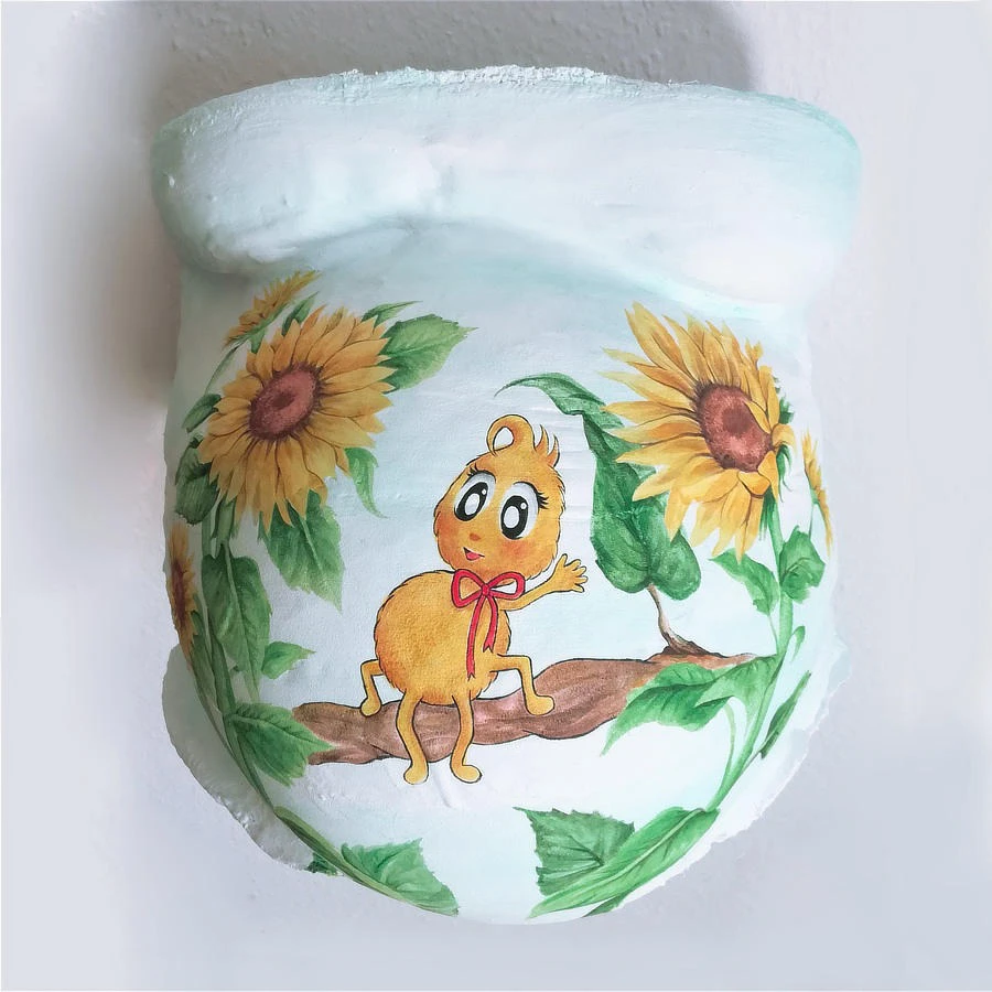 Gipsbauchbemalung mit strahlenden Sonnenblumen und fröhlicher Kinderfigur auf Ast – kreative Erinnerung an die Schwangerschaft
