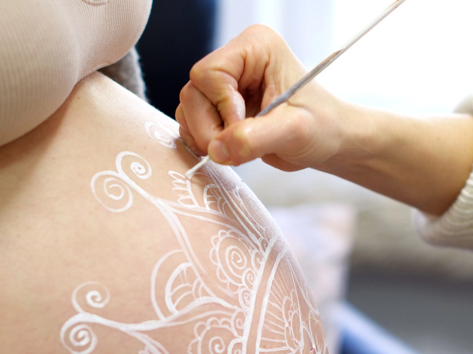 Detailaufnahme einer handgemalten Babybauchbemalung mit weißem Mandala-Motiv von cy-DESIGN