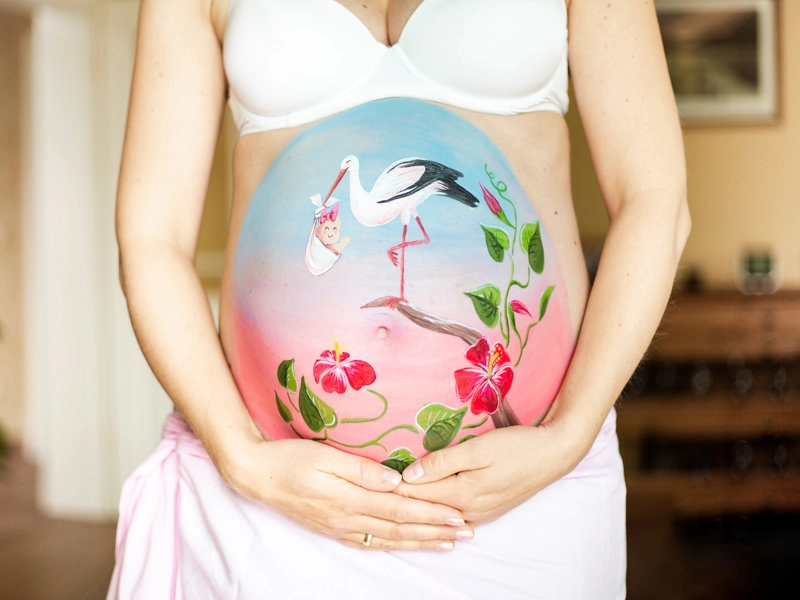 Bemalung auf Schwangerschaftsbauch mit Storch und Baby