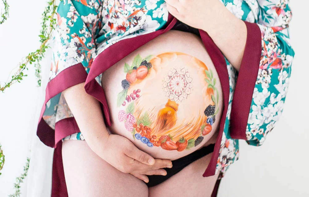 Bemalung auf Schwangerschaftsbauch mit einem Bären und Beeren
