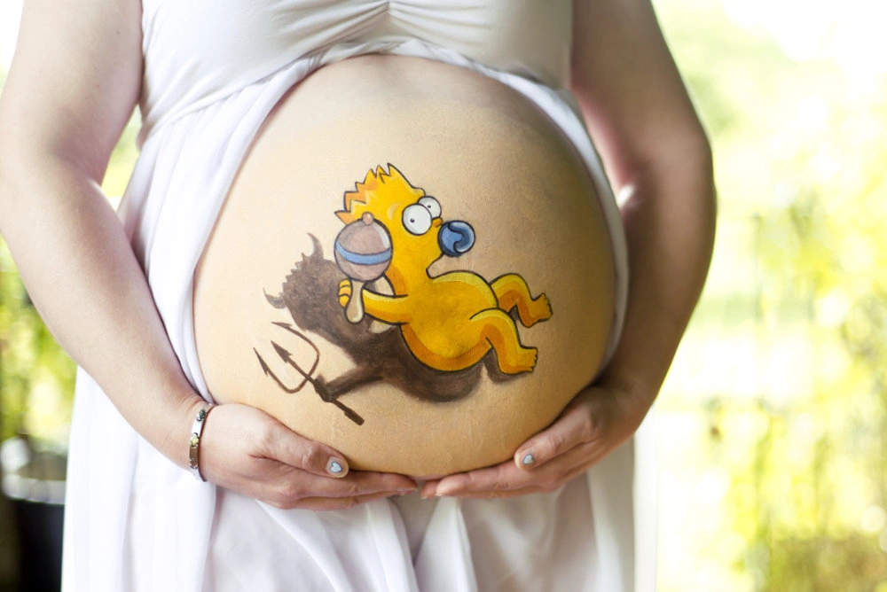 Babybauchbemalung mit Cartoon-Figur inspiriert von Baby Bart Simpson – humorvoller Schatten als kleiner Teufel mit Dreizack, kreative Bauchkunst zur Schwangerschaft