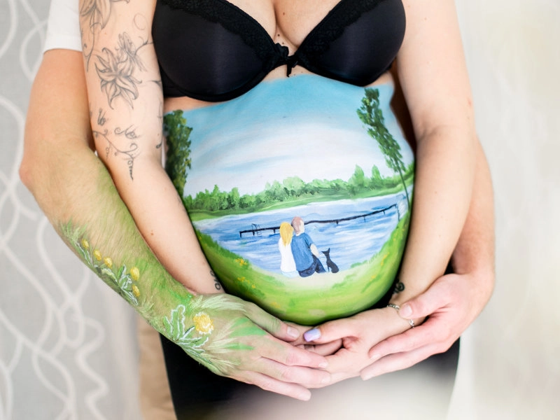 Bemalung auf Schwangerschaftsbauch mit einer Familie am See