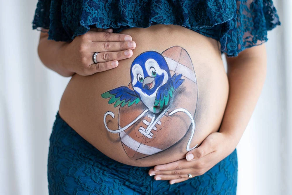 Bemalung auf Schwangerschaftsbauch mit einem Football Vogelbaby
