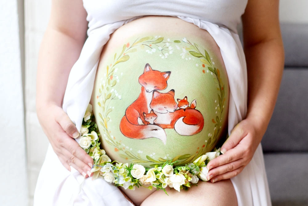 Babybauchbemalung mit liebevoller Fuchsfamilie im grünen Blätterkranz – verspieltes und sanftes Naturmotiv als Erinnerung an die Schwangerschaft