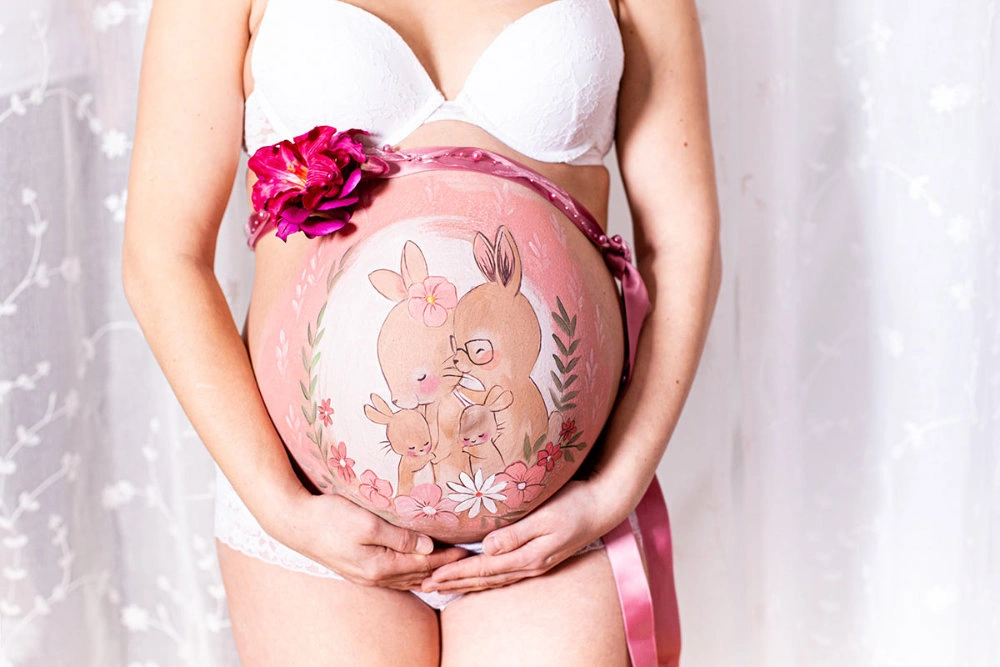 Bemalung auf Schwangerschaftsbauch mit einer Hasenfamilie
