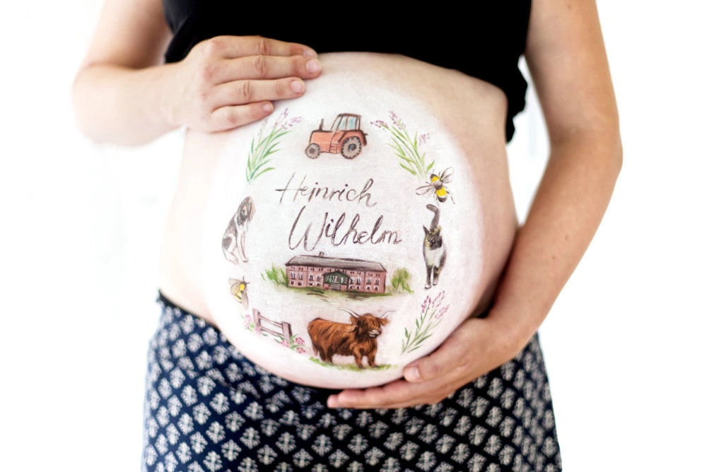 Individuelle Babybauchbemalung mit Bauernhof-Motiven und dem Namen Heinrich Wilhelm – mit Tieren, Traktor und Hofgebäude