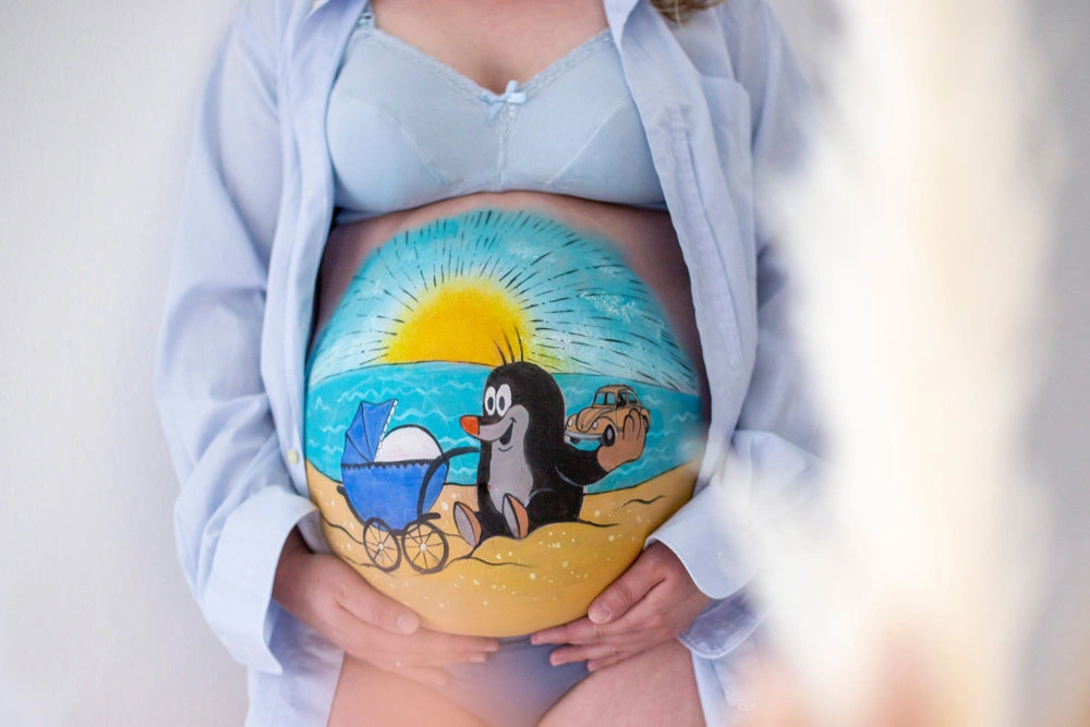 Bemalung auf Schwangerschaftsbauch mit dem kleinen Maulwurf am Strand

