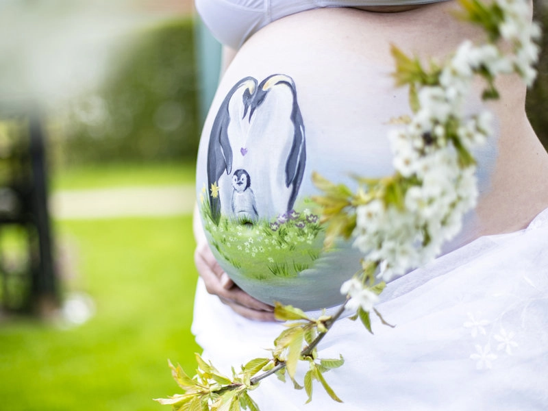 Bemalung auf Schwangerschaftsbauch mit einer Pinguin Familie