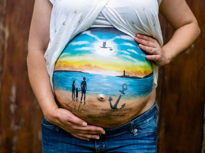 Bemalung auf Schwangerschaftsbauch Familie am Strand