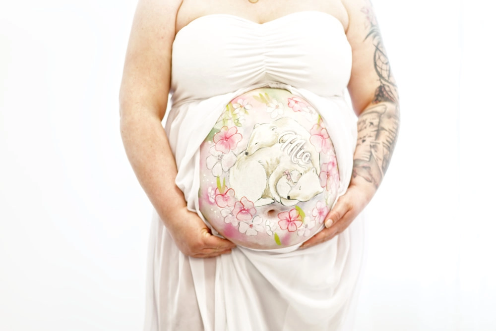 Zarte Babybauchbemalung mit weißen Füchsen, Kirschblüten und Namenszug „Mio“ – emotionales Naturmotiv in sanften Rosatönen für eine liebevolle Erinnerung