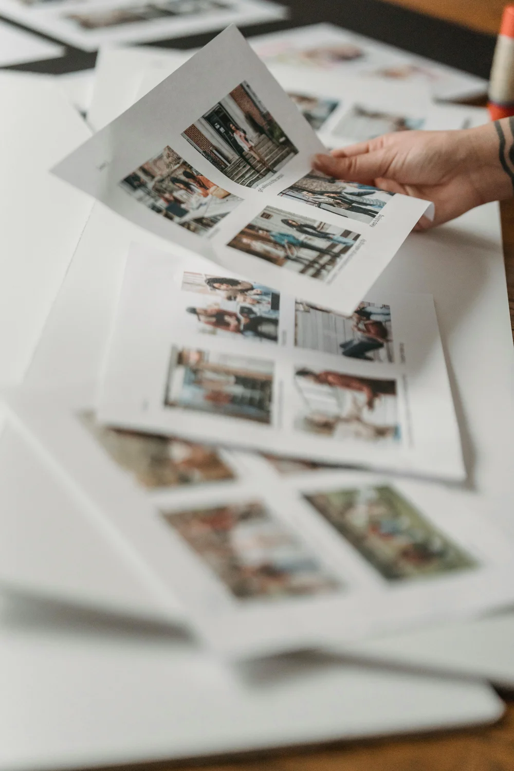 Hand hält eine Auswahl gedruckter Fotos – Auswahl der schönsten Bilder nach dem Babybauch-Fotoshooting